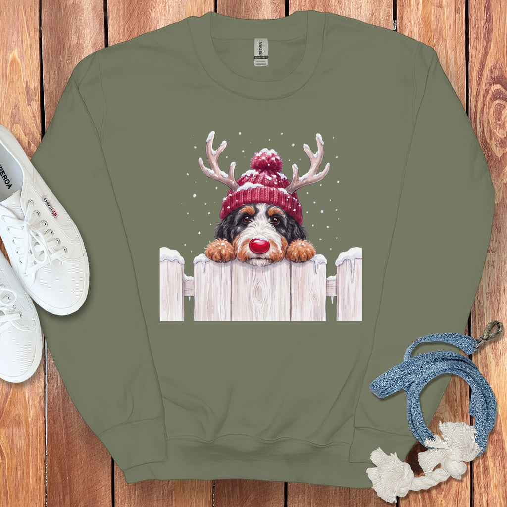 Bernese Mountain Dog wearing a red Santa hat and antlers peeks over a fence.