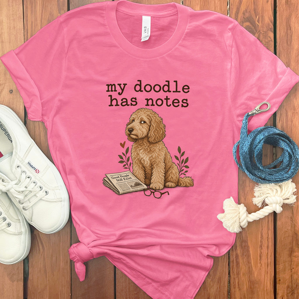 Pink t-shirt with "my doodle has notes" and a dog with newspaper and glasses.