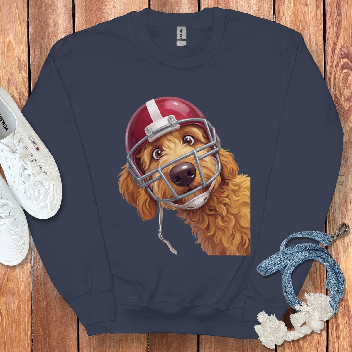 Goldendoodle wearing a red football helmet and facemask on a navy sweatshirt.