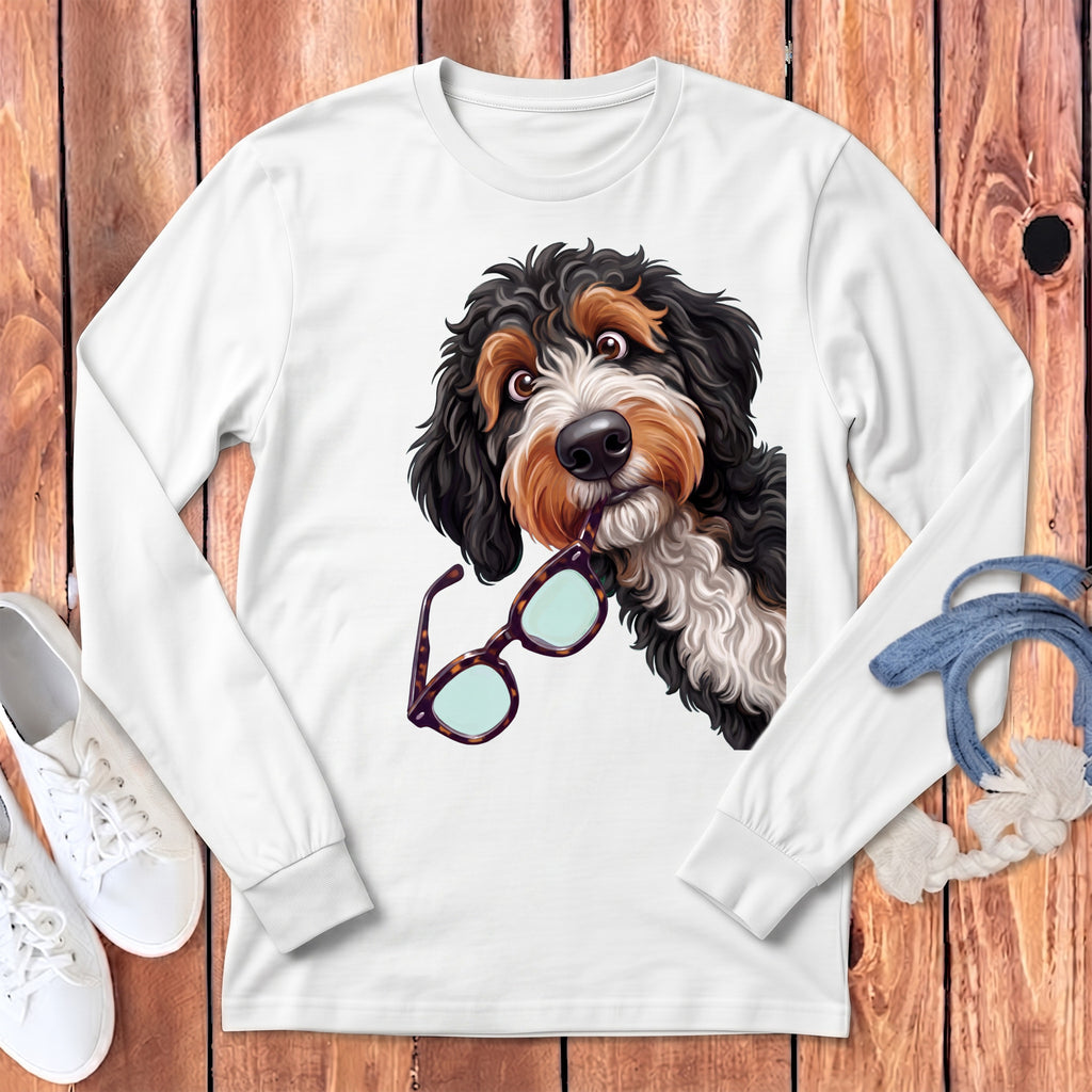 A white long-sleeved shirt featuring a graphic of a fluffy black and brown dog holding glasses in its mouth.