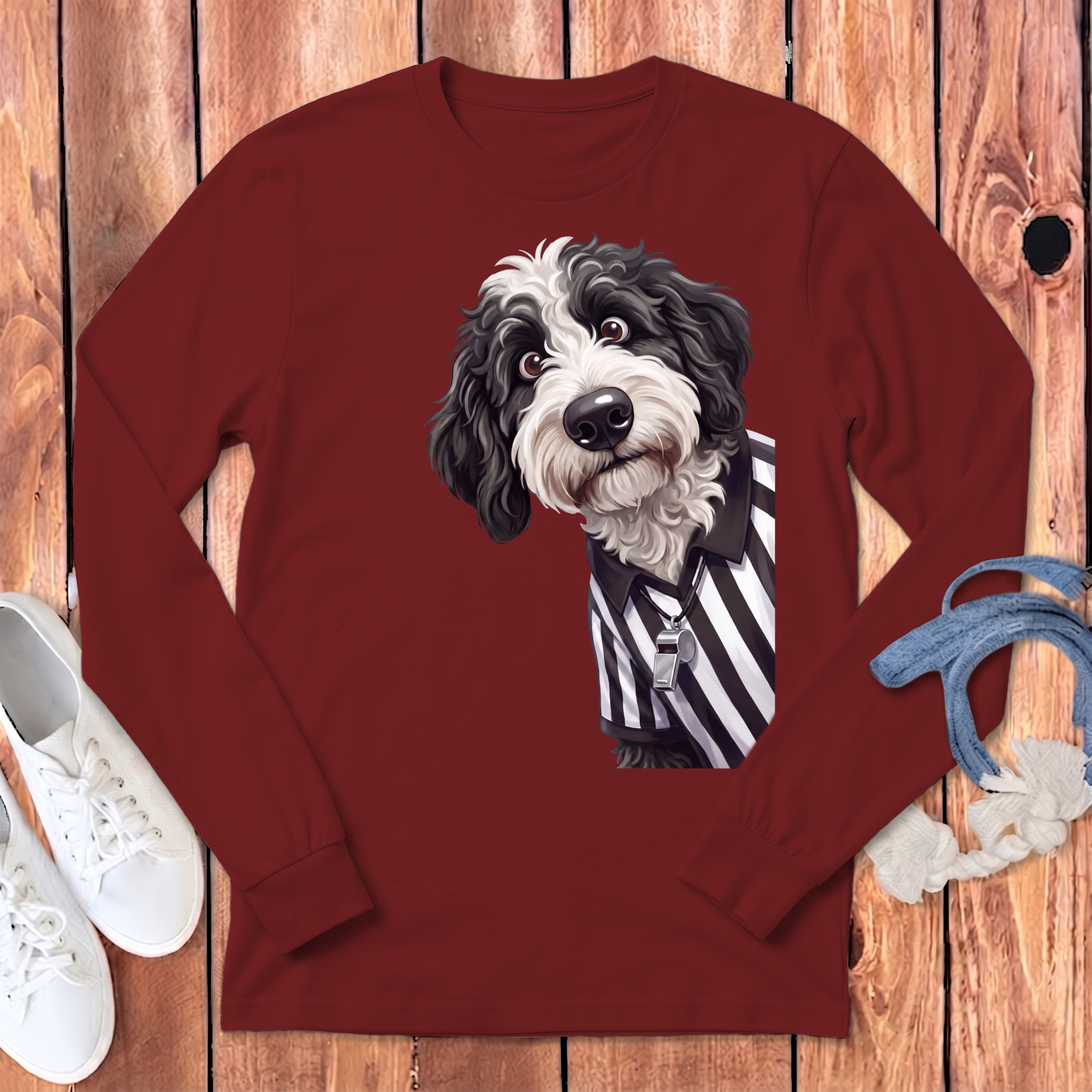 Bernedoodle dog wearing a referee shirt with a whistle on a maroon long-sleeved shirt.