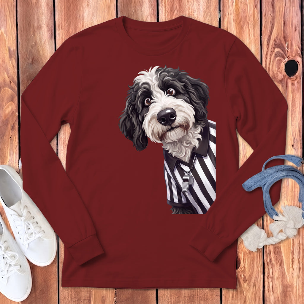Bernedoodle dog wearing a referee shirt with a whistle on a maroon long-sleeved shirt.