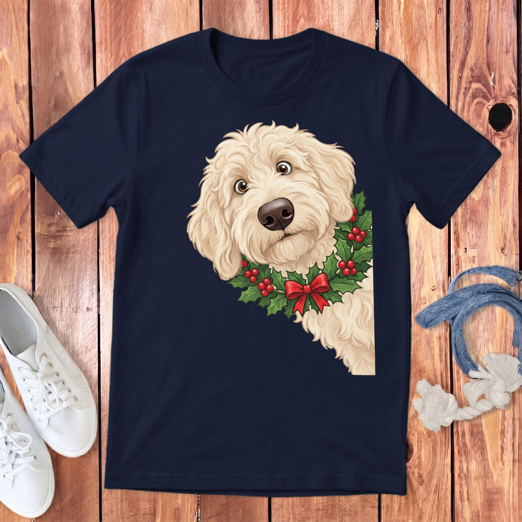 Goldendoodle dog peeking from behind Christmas holly and red bow on a navy shirt.