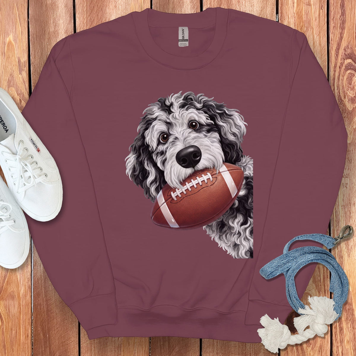 Maroon sweatshirt with a black and white dog holding a football.