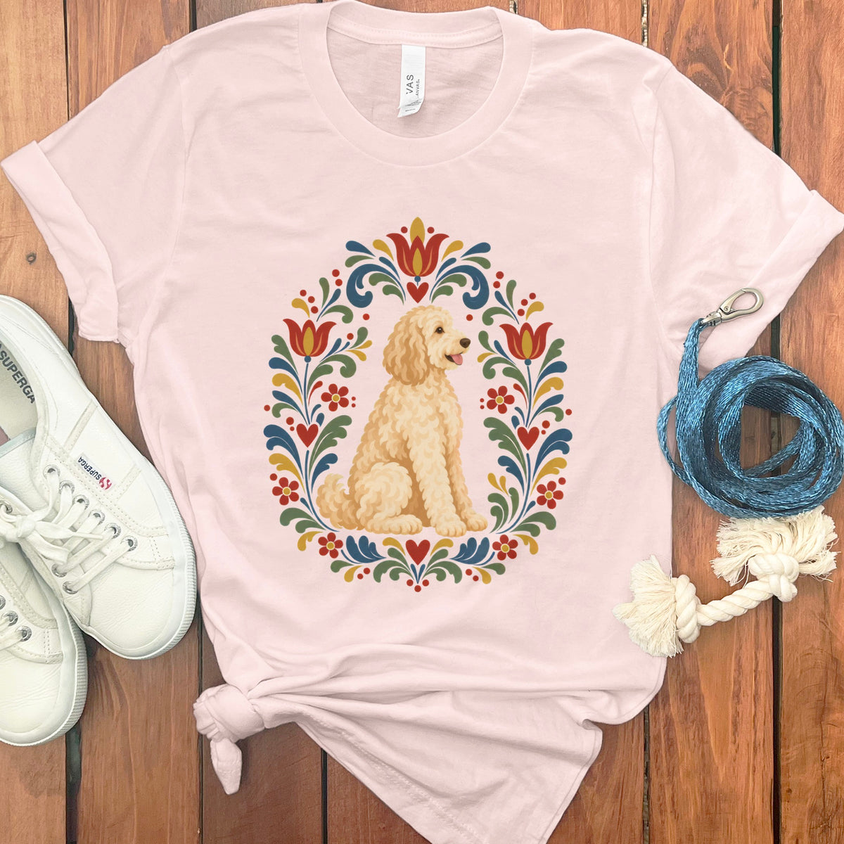 Light pink t-shirt with a cream doodle dog inside a colorful floral circle.