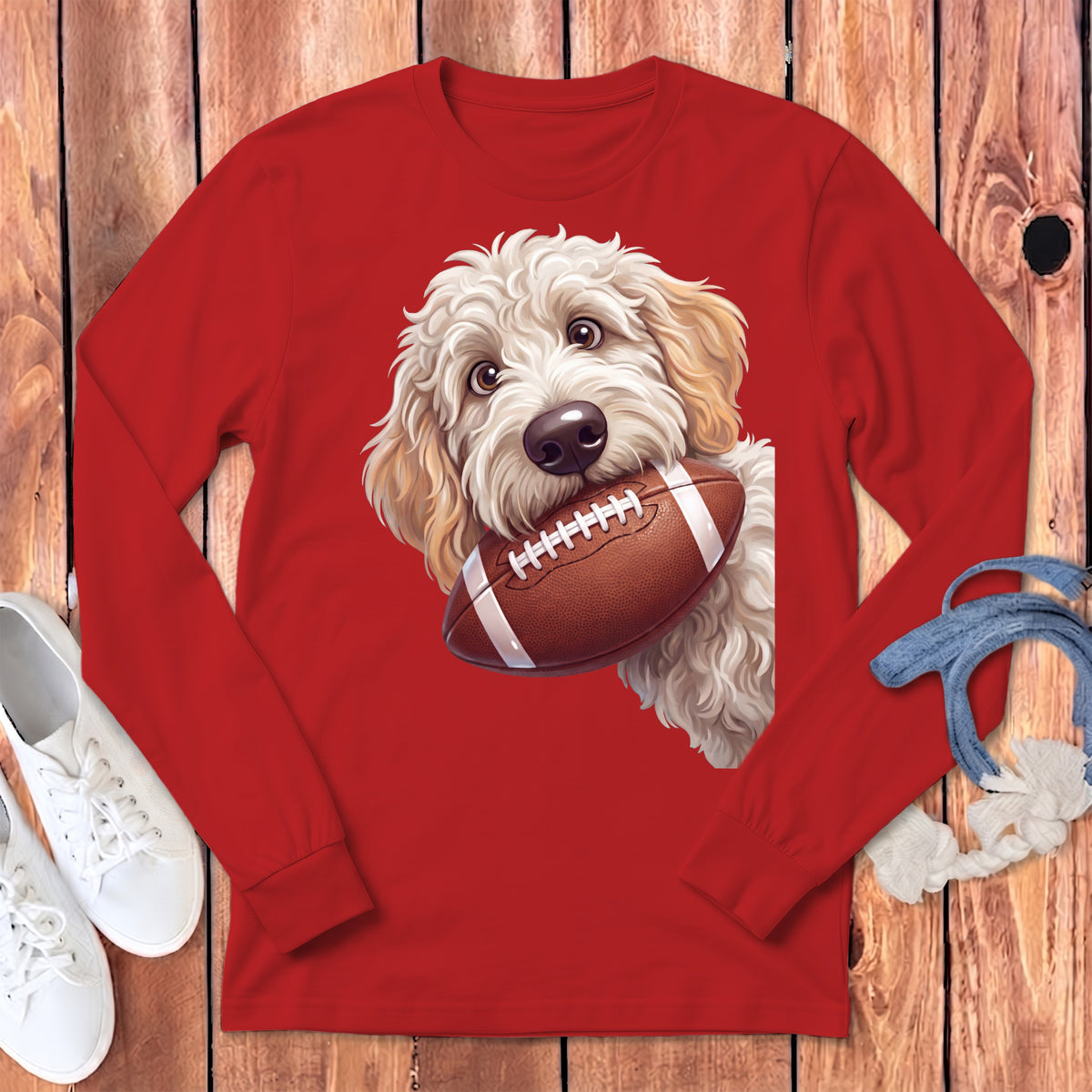 Red long-sleeve t-shirt featuring a fluffy golden retriever puppy holding a football in its mouth.