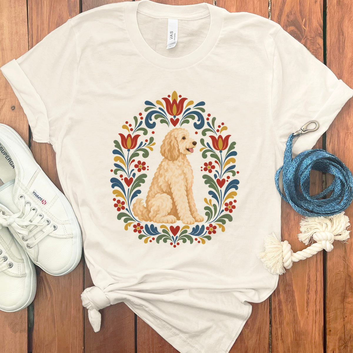 Cream t-shirt with a golden doodle dog inside a floral folk art wreath design.