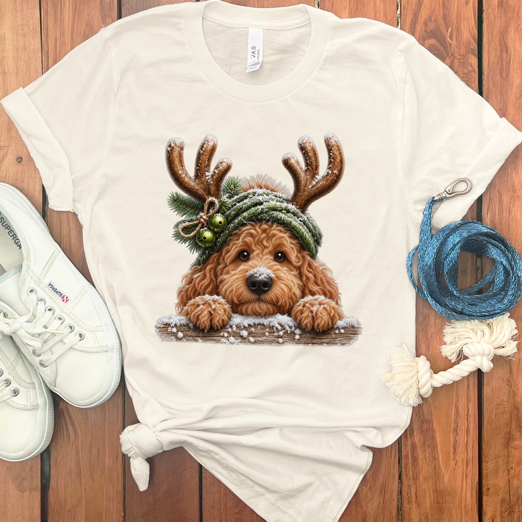 Cream t-shirt with a Christmas-themed doodle dog graphic wearing antlers and a hat.