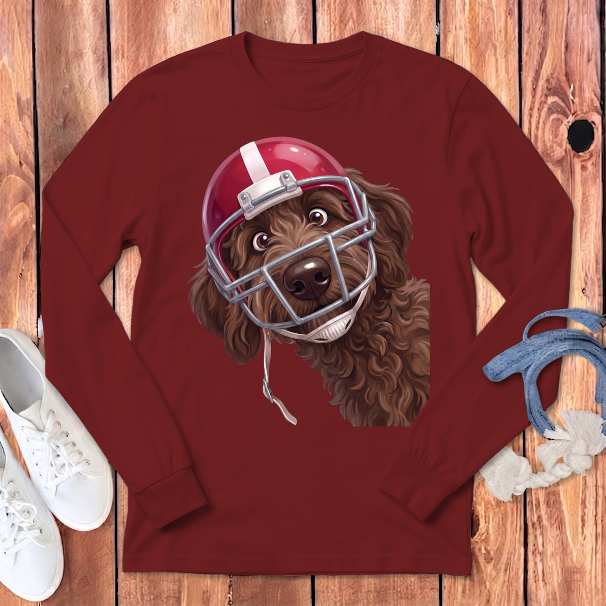 Brown dog wearing a red and white football helmet on a maroon long-sleeve shirt.