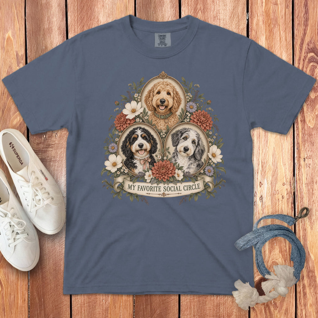 A slate-blue t-shirt featuring a vintage floral graphic of three doodle dogs with the text MY FAVORITE SOCIAL CIRCLE.