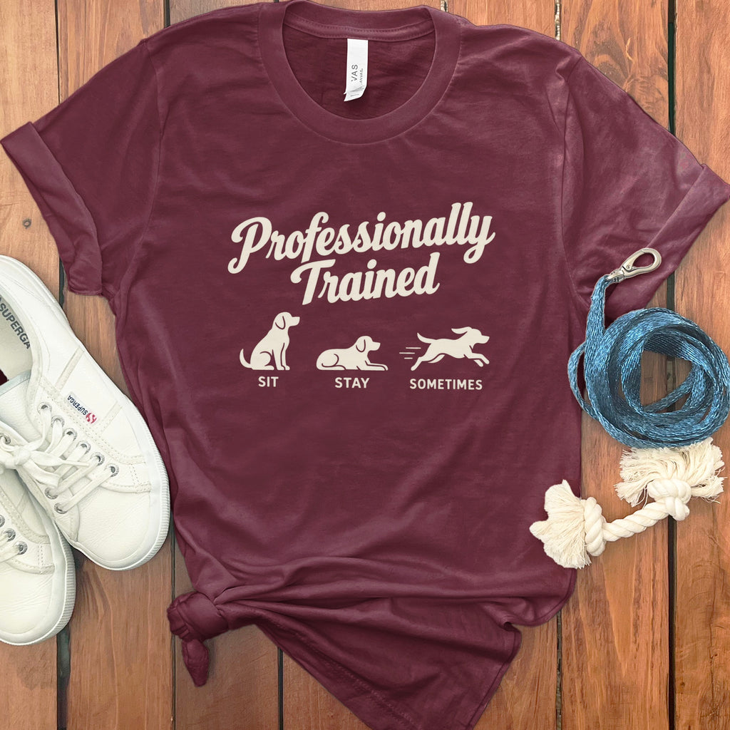 Maroon t-shirt with "Professionally Trained" and dog graphics for sit, stay, and sometimes.