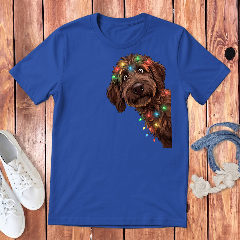 Blue t-shirt with brown dog peeking around corner wearing colorful Christmas lights.