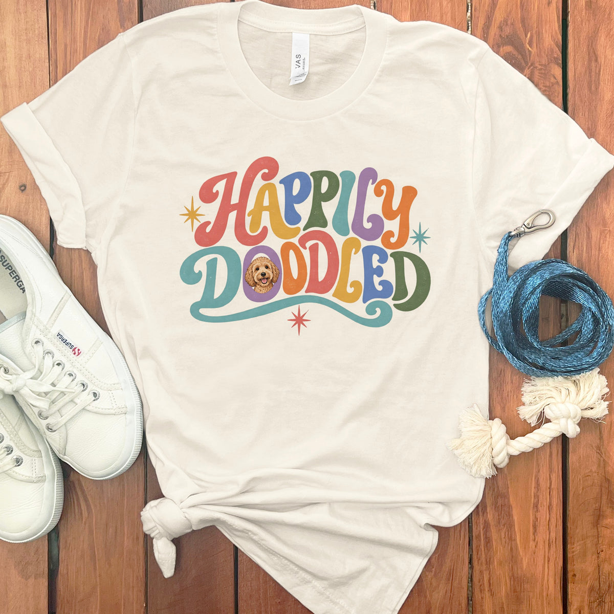 Cream t-shirt with colorful "Happily Doodled" text and dog illustration.