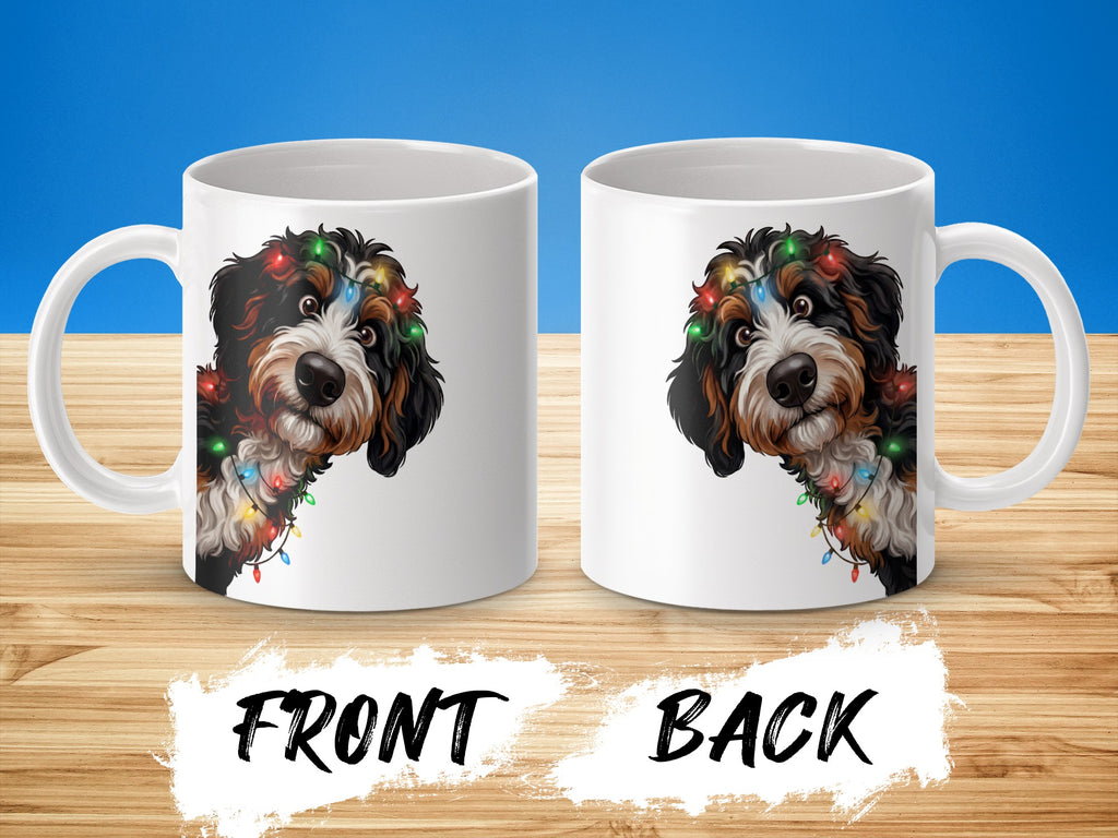 Two white mugs display a Bernese Mountain Dog with colorful Christmas lights.