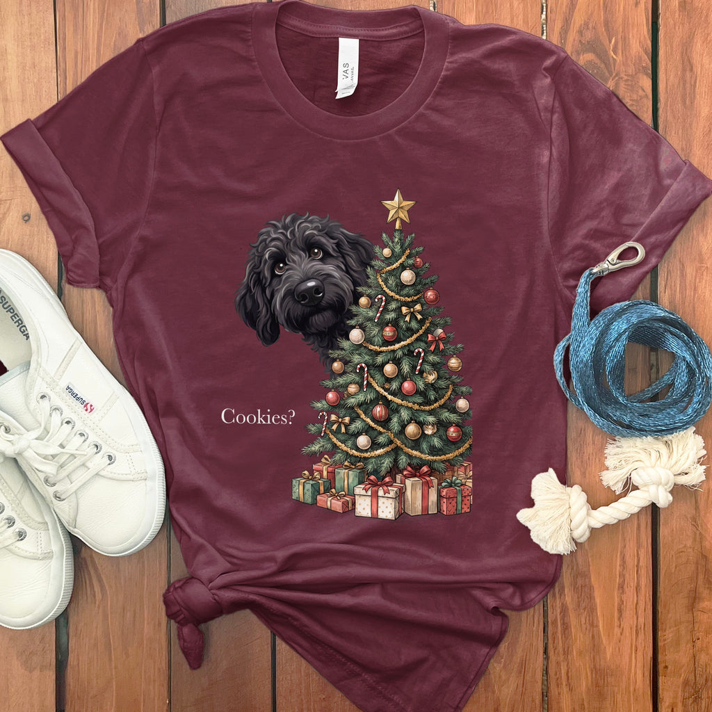Maroon t-shirt with black dog peeking from behind a decorated Christmas tree and gifts.