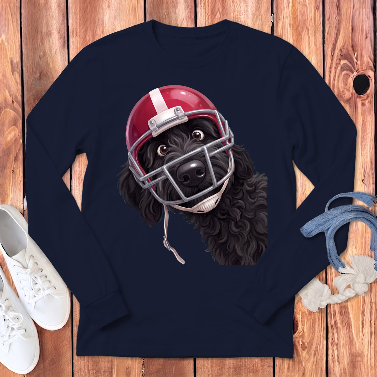 Black dog wearing a red football helmet peeking from a navy long-sleeve shirt.