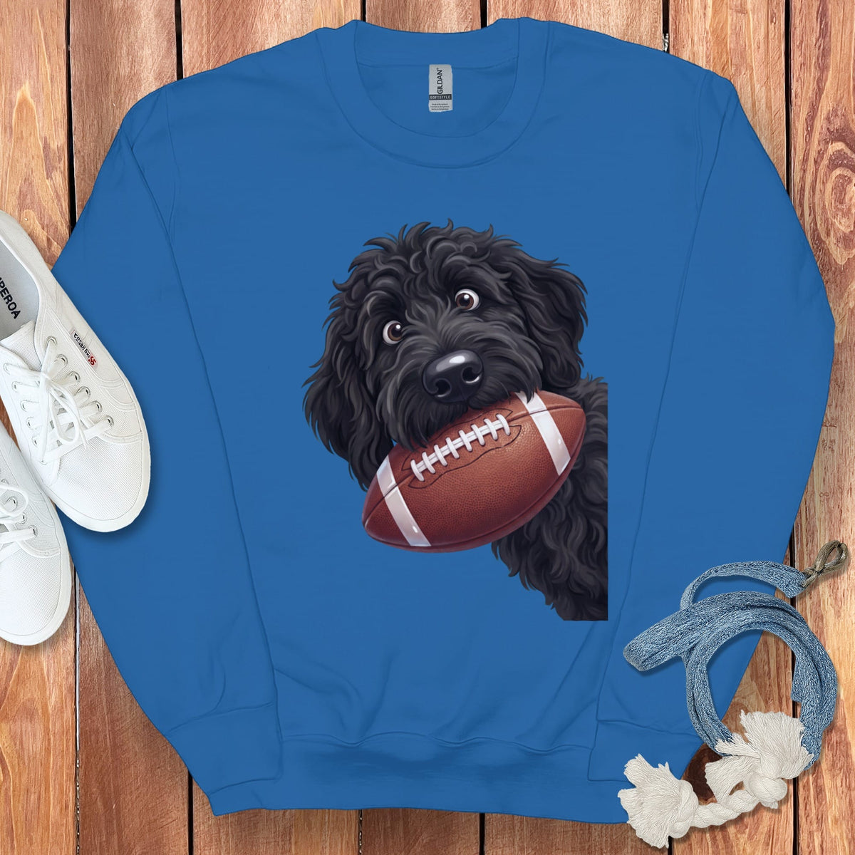 Blue sweatshirt with a black doodle dog graphic holding a football.