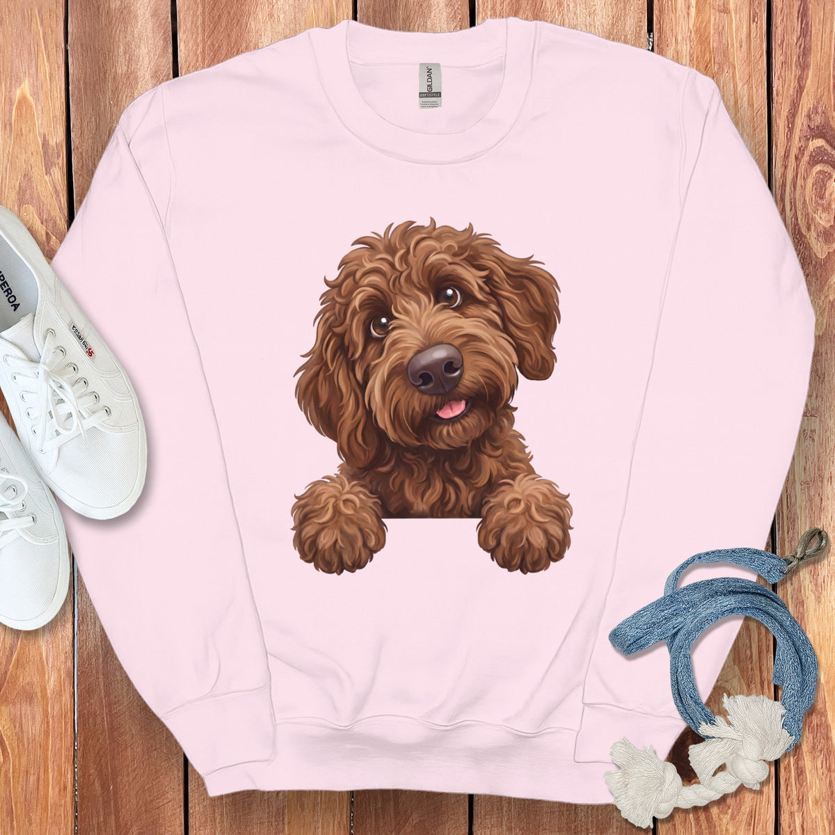 Pink sweatshirt with a graphic of a cute brown doodle dog peeking over a white border.