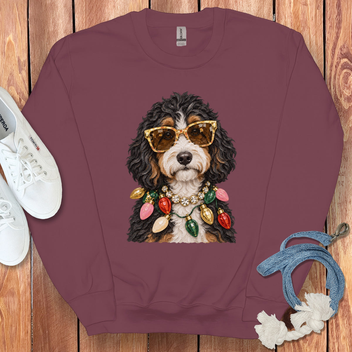 Bernese Mountain Dog wearing sunglasses and Christmas lights on a maroon sweatshirt.