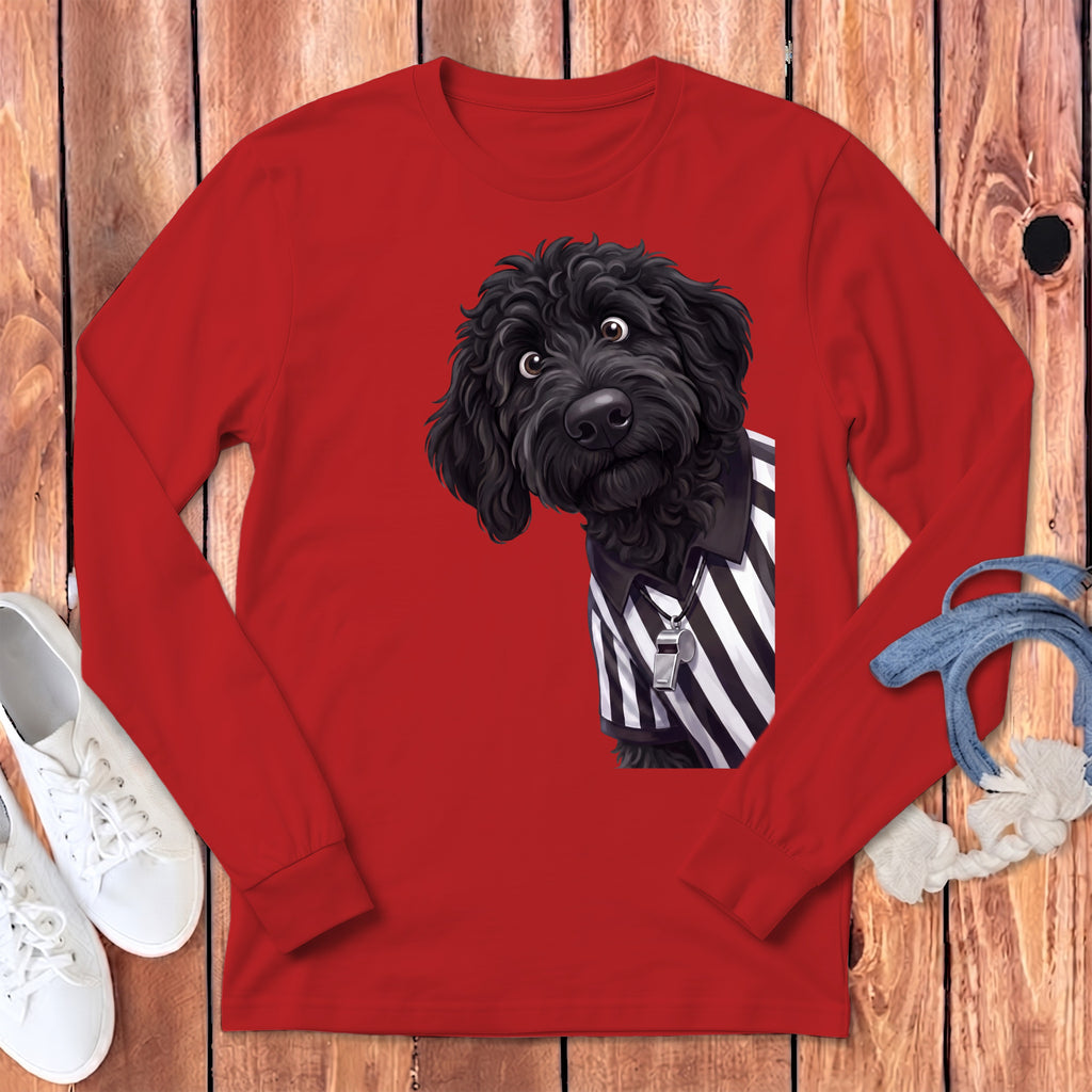 Black doodle dog wearing a referee shirt with whistle on a red long sleeve shirt.