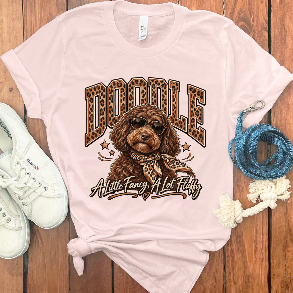 Pink t-shirt with brown doodle dog wearing sunglasses and scarf, text "A Little Fancy, A Lot Fluffy".