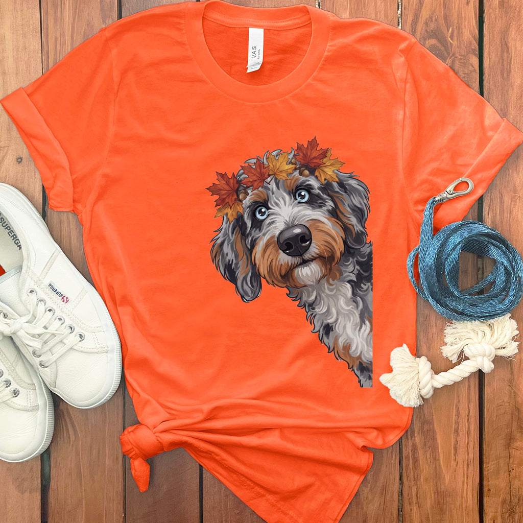 Orange t-shirt with a doodle dog wearing a fall leaf crown and a leash.