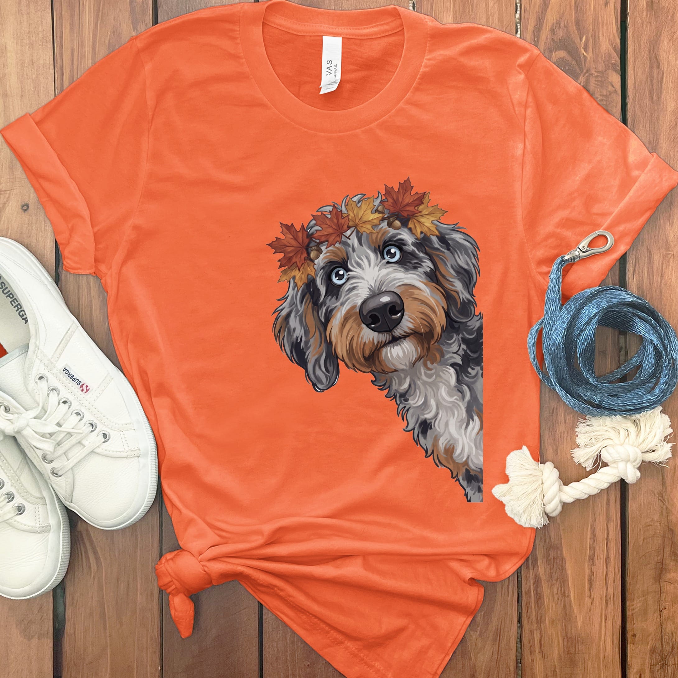 Orange t-shirt with a doodle dog wearing a fall leaf crown and a leash.