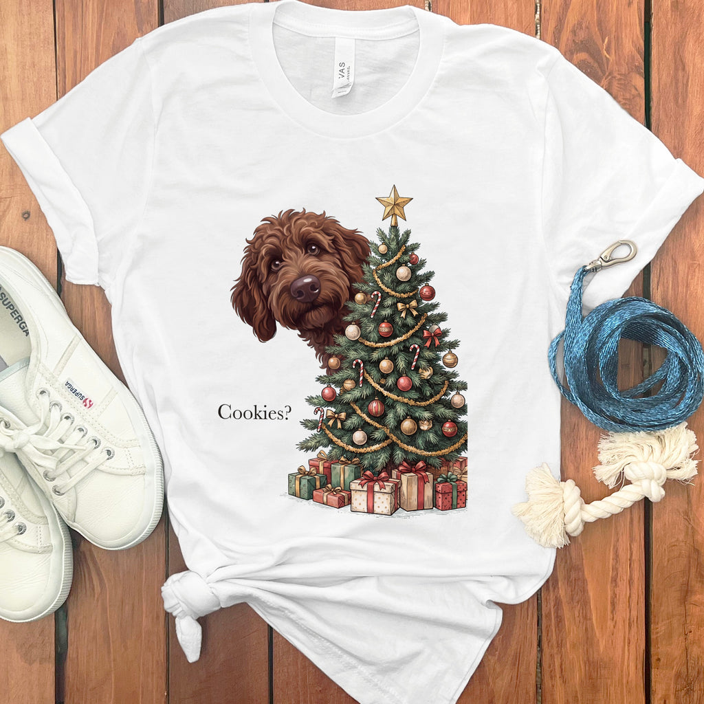 Brown doodle peeking from behind a Christmas tree with gifts and the text "Cookies?".