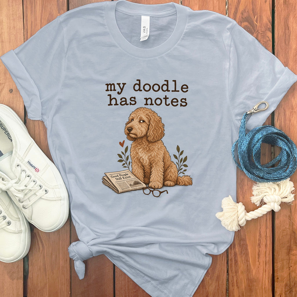 Light blue t-shirt with a doodle dog, newspaper, glasses, and text that reads "my doodle has notes."