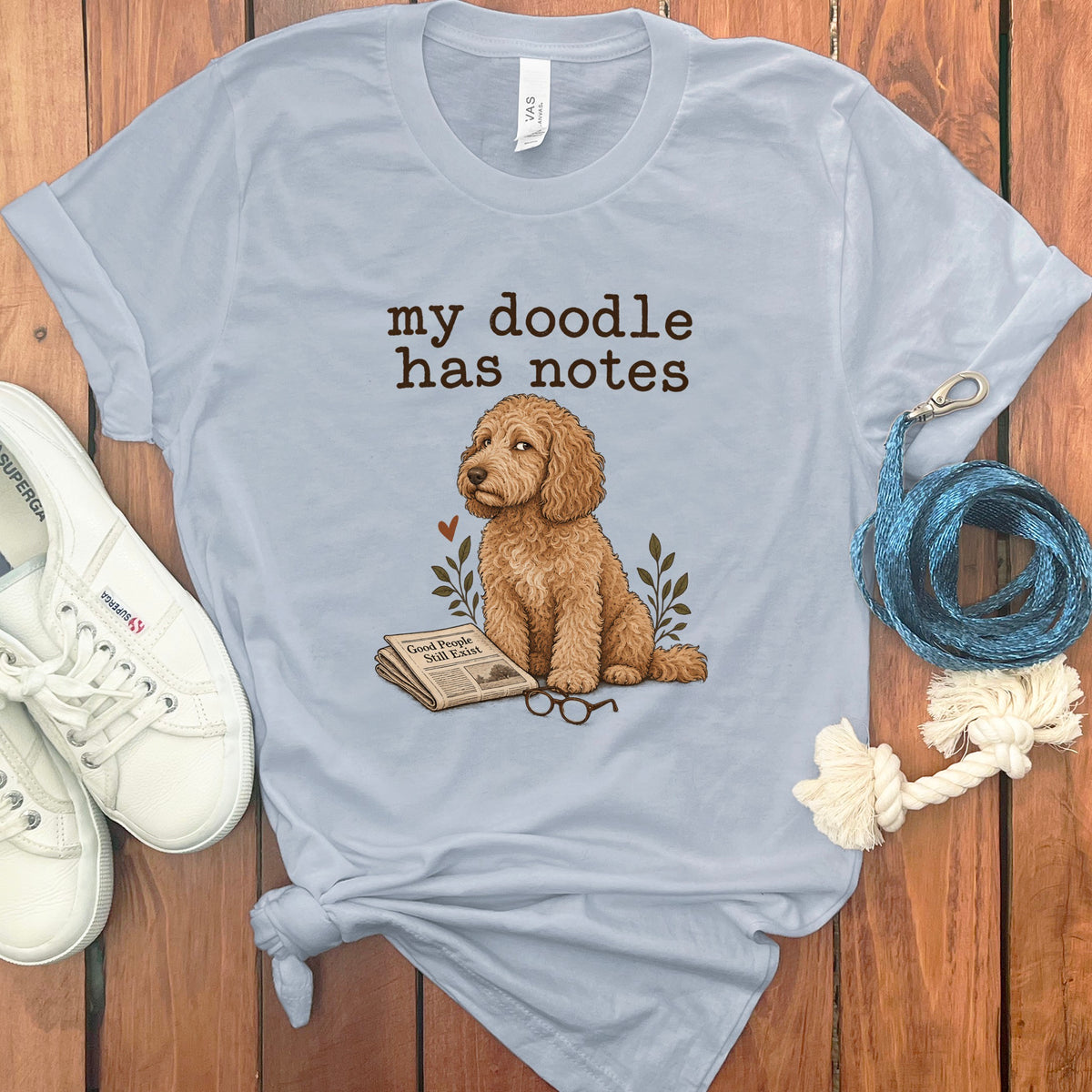 Light blue t-shirt with a doodle dog, newspaper, glasses, and text that reads "my doodle has notes."