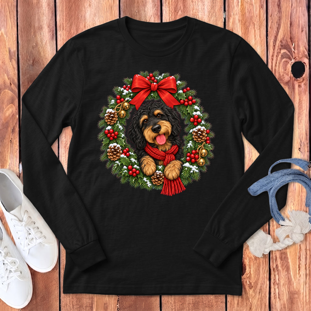 Black long-sleeve t-shirt featuring a doodle dog graphic wearing a red scarf inside a Christmas wreath.