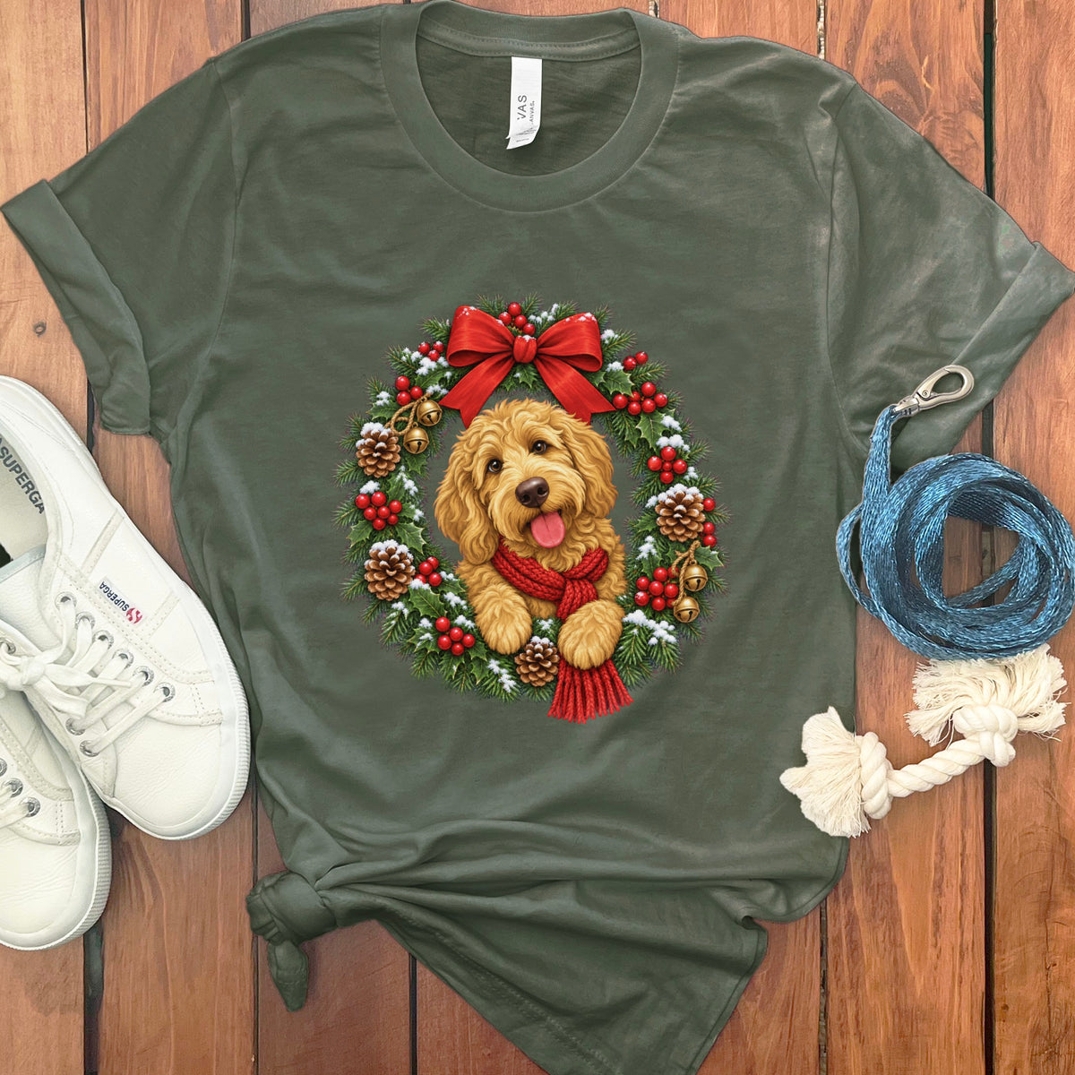 Olive green t-shirt featuring a goldendoodle puppy wearing a red scarf inside a Christmas wreath.