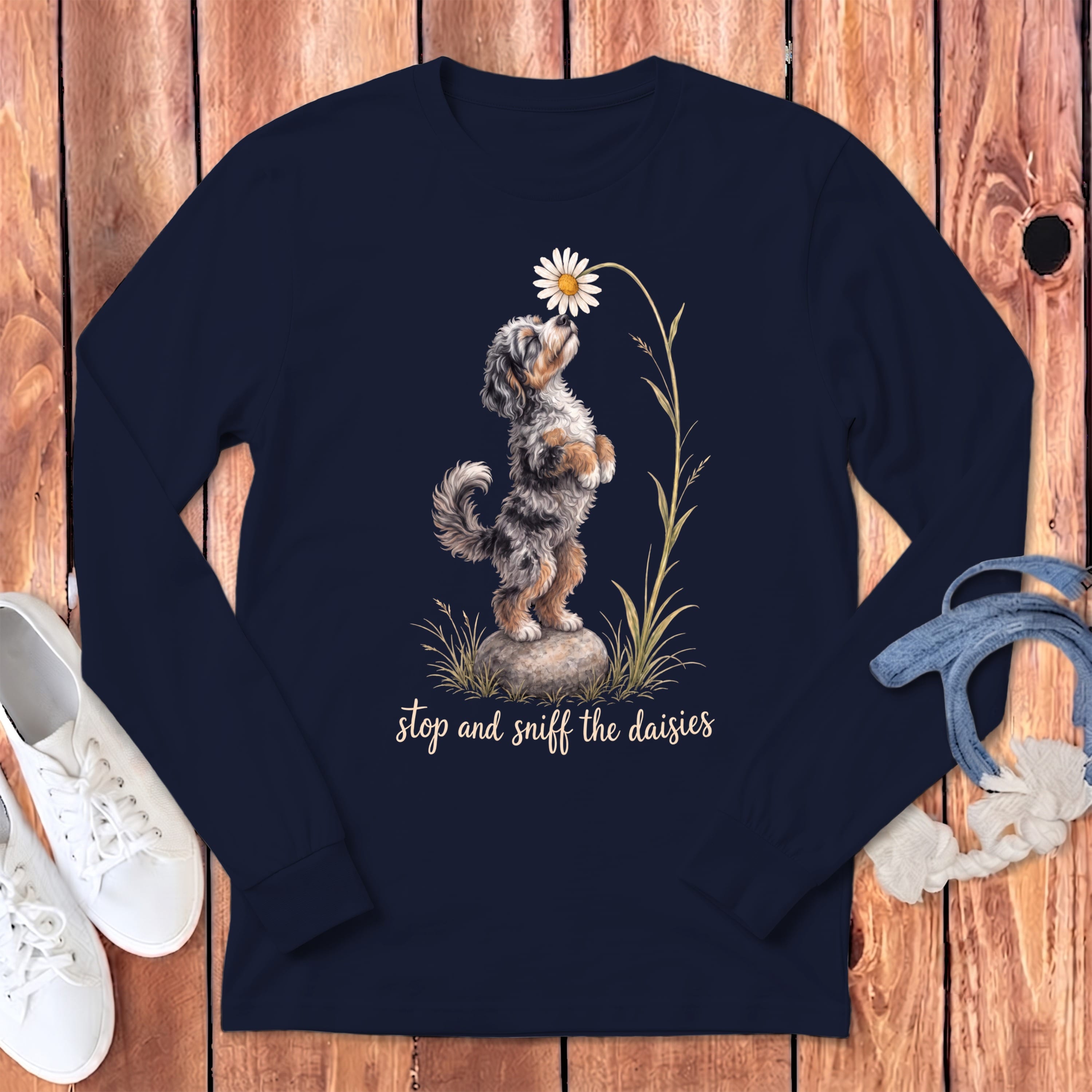 Navy long sleeve shirt with a fluffy dog sniffing a daisy and text "stop and sniff the daisies".