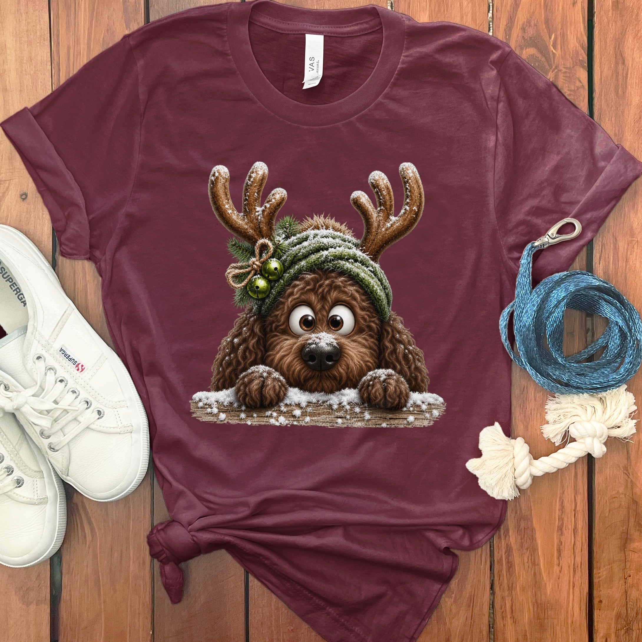 Maroon t-shirt featuring a brown dog wearing reindeer antlers and a knit hat.