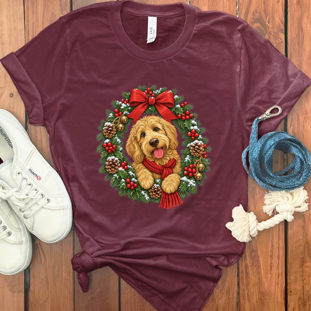 Maroon crewneck t-shirt featuring a doodle dog wearing a red scarf inside a Christmas wreath.