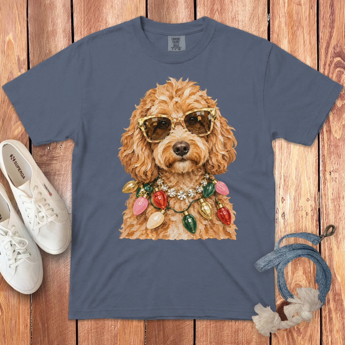 Brown doodle dog wearing sunglasses and festive Christmas lights necklace on grey t-shirt.