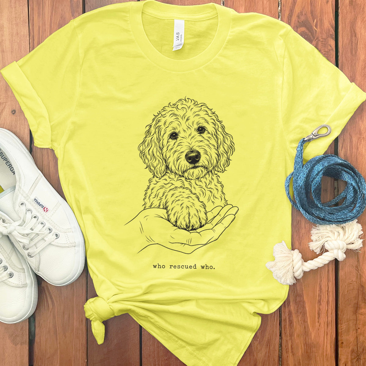 Yellow t-shirt with line drawing of dog paw on hand and text "who rescued who."