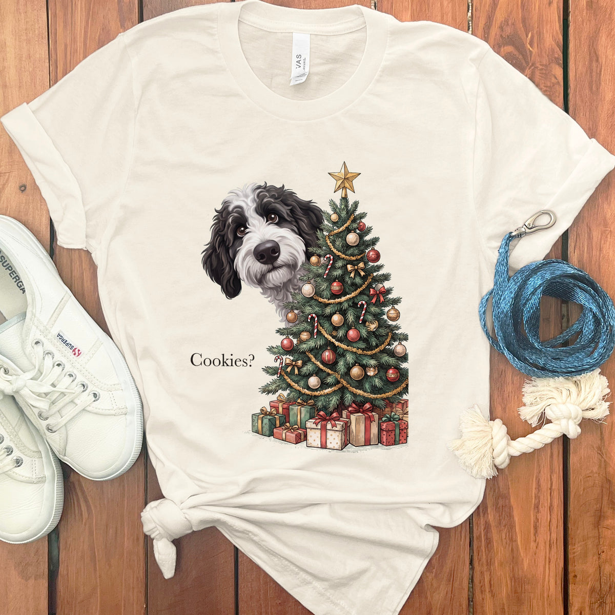 Black and white dog peeking from behind a decorated Christmas tree, with text "Cookies?".