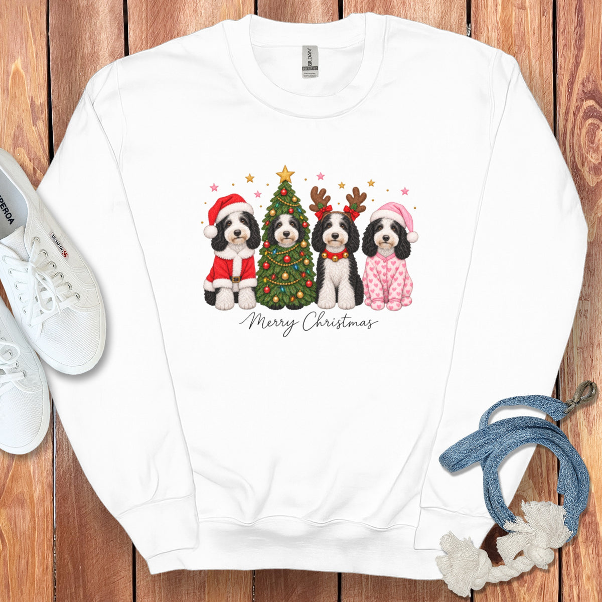White crewneck sweatshirt featuring a graphic of four dogs in Christmas costumes around a decorated tree and the text Merry Christmas.