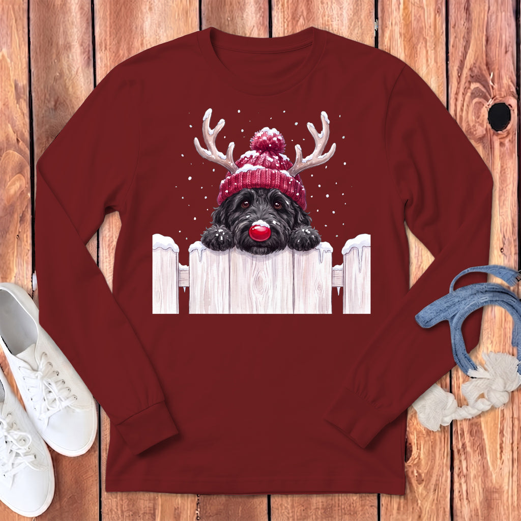 Black dog wearing a red beanie with antlers and a red nose, peeking over a fence.
