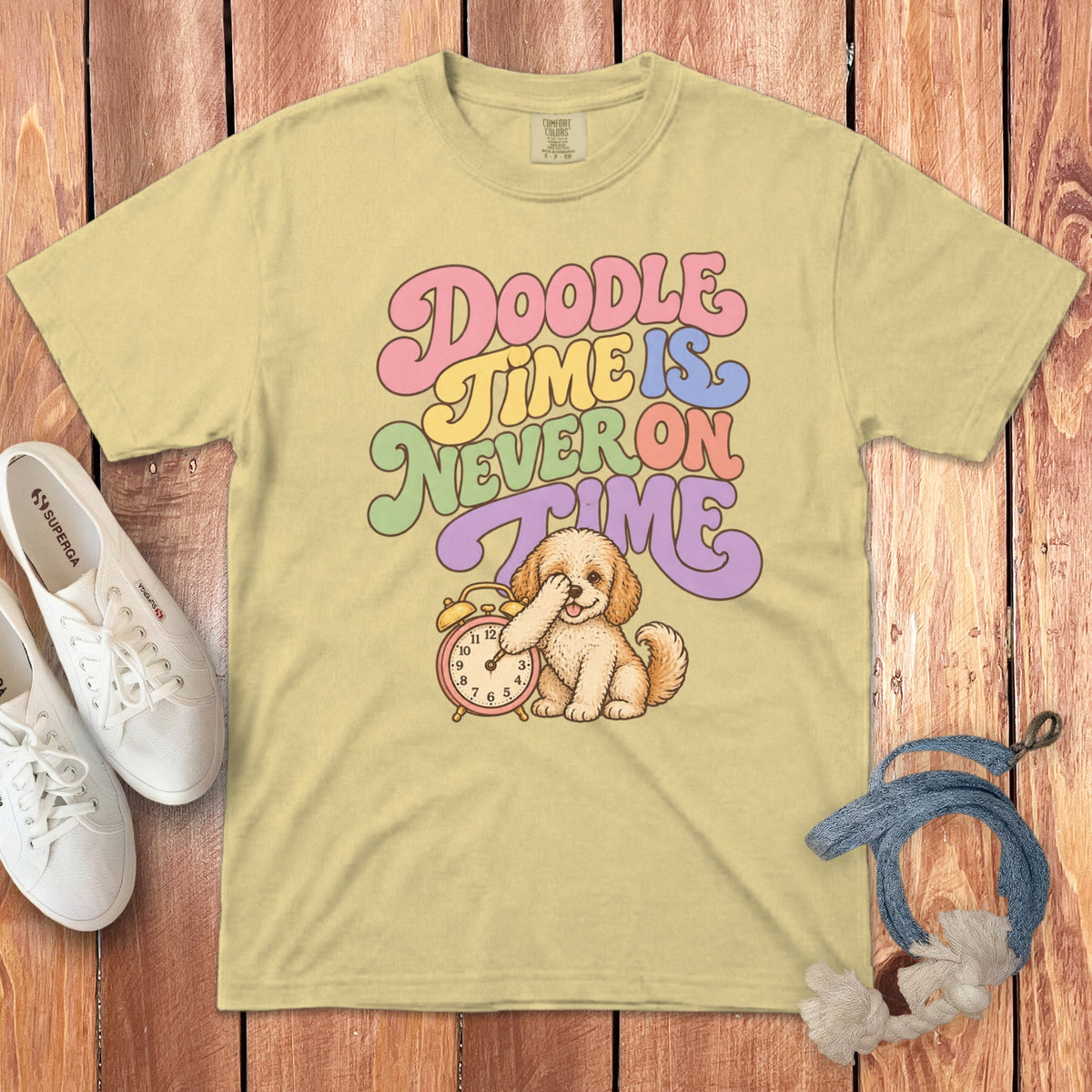 Light yellow t-shirt with a cartoon dog covering its eyes next to an alarm clock.