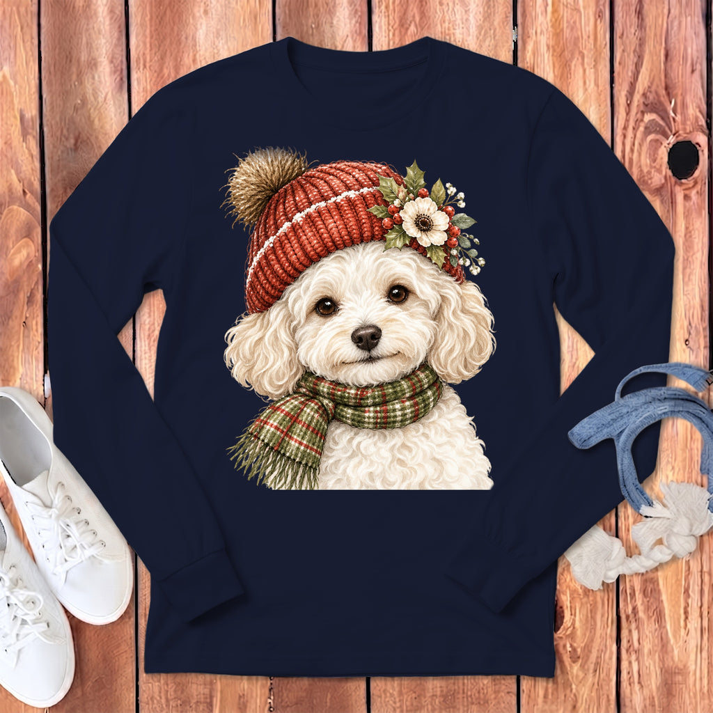 Fluffy white dog wearing a red pom-pom hat and plaid scarf on a navy shirt.