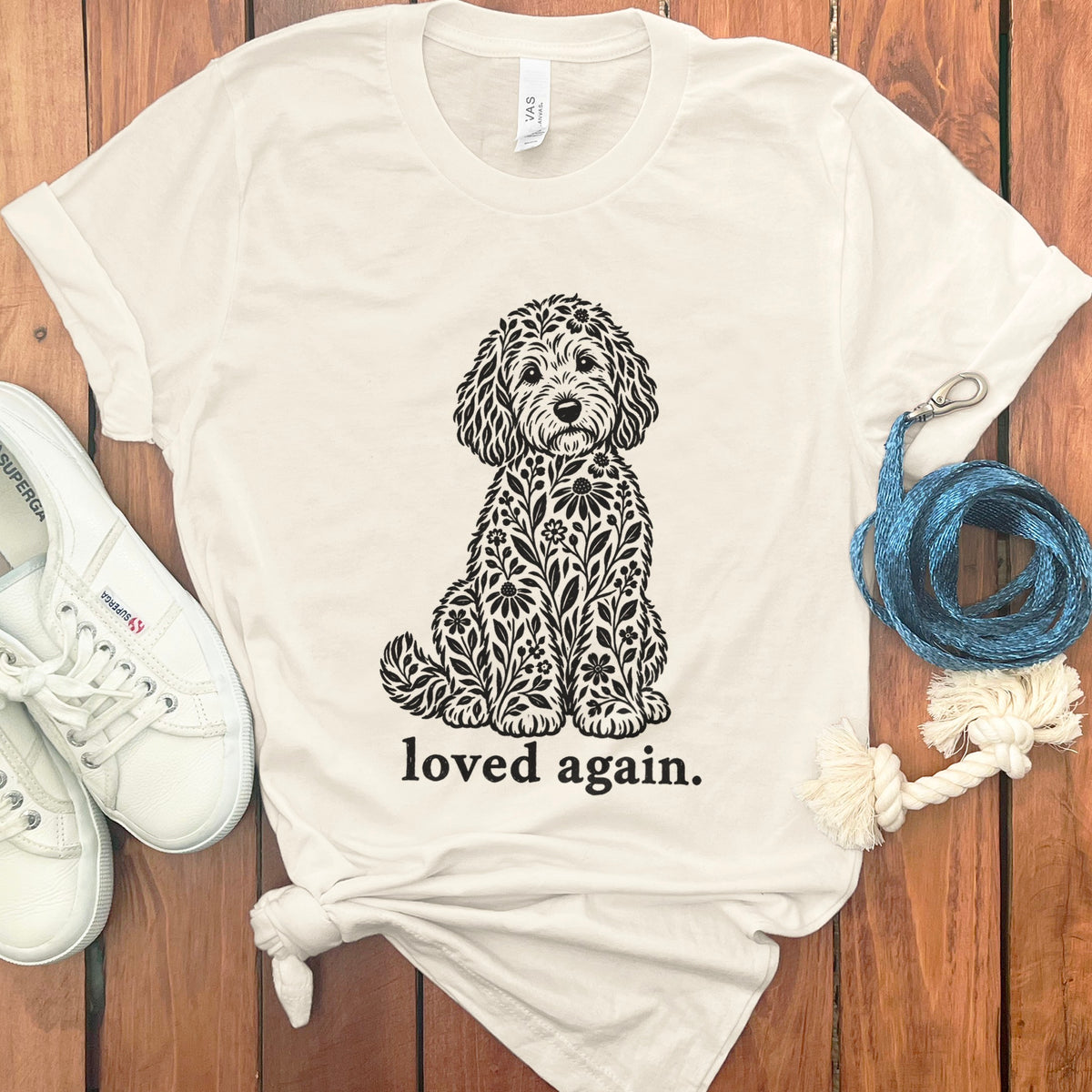White t-shirt with black floral dog graphic and text "loved again."