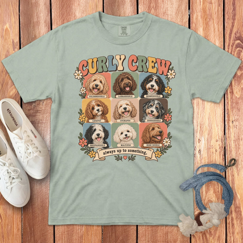 A light sage green t-shirt with a retro graphic of nine doodle dog breeds, labeled Curly Crew.