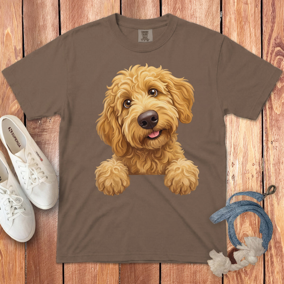 Brown t-shirt with a printed cartoon goldendoodle dog, white sneakers, and dog toy.