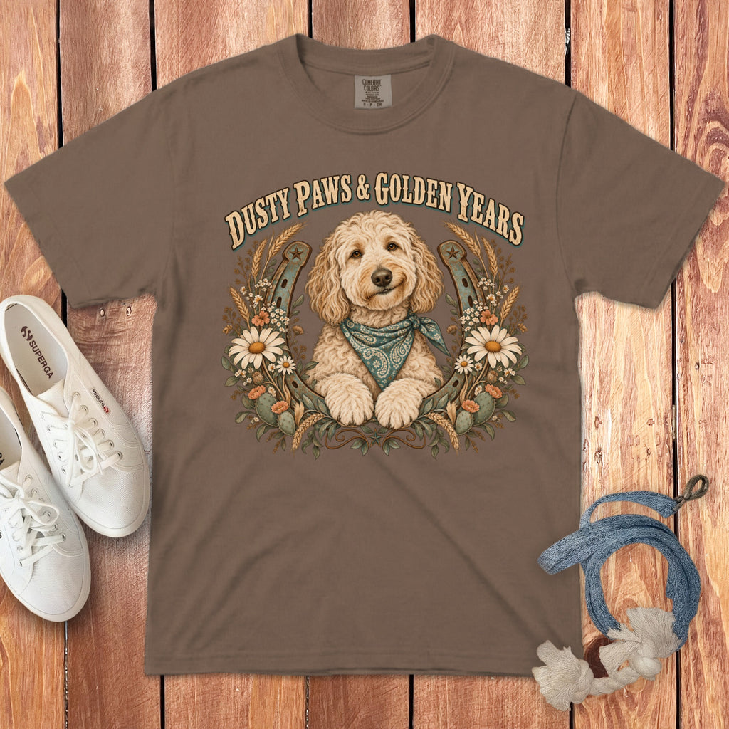 Brown crewneck t-shirt featuring a golden retriever graphic, text, horseshoes, and flowers, laid on wood.