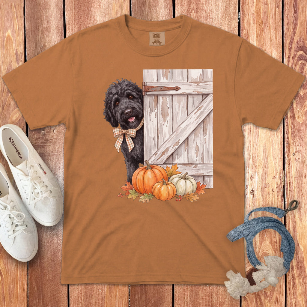 Black dog wearing bow tie peeking from behind a rustic door with pumpkins.