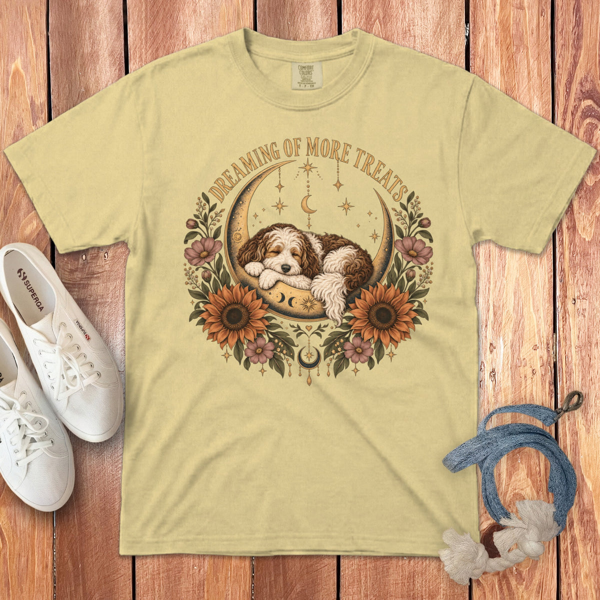 Yellow t-shirt with a graphic of a sleeping puppy inside a crescent moon, sunflowers, and the text "Dreaming of More Treats."