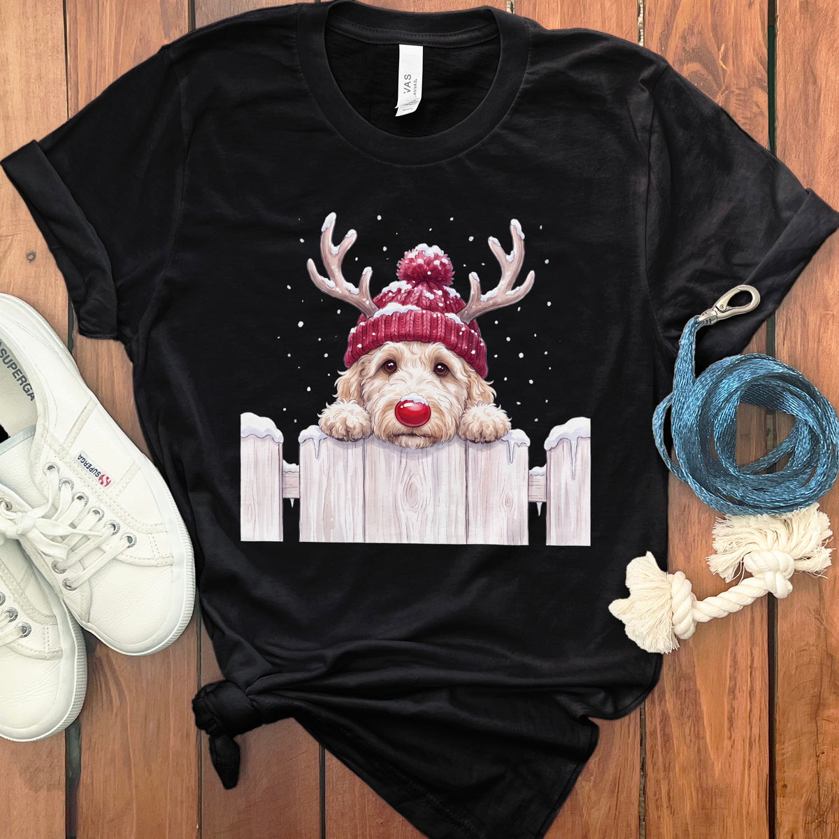 Black t-shirt with a fluffy dog wearing a red beanie and reindeer antlers.