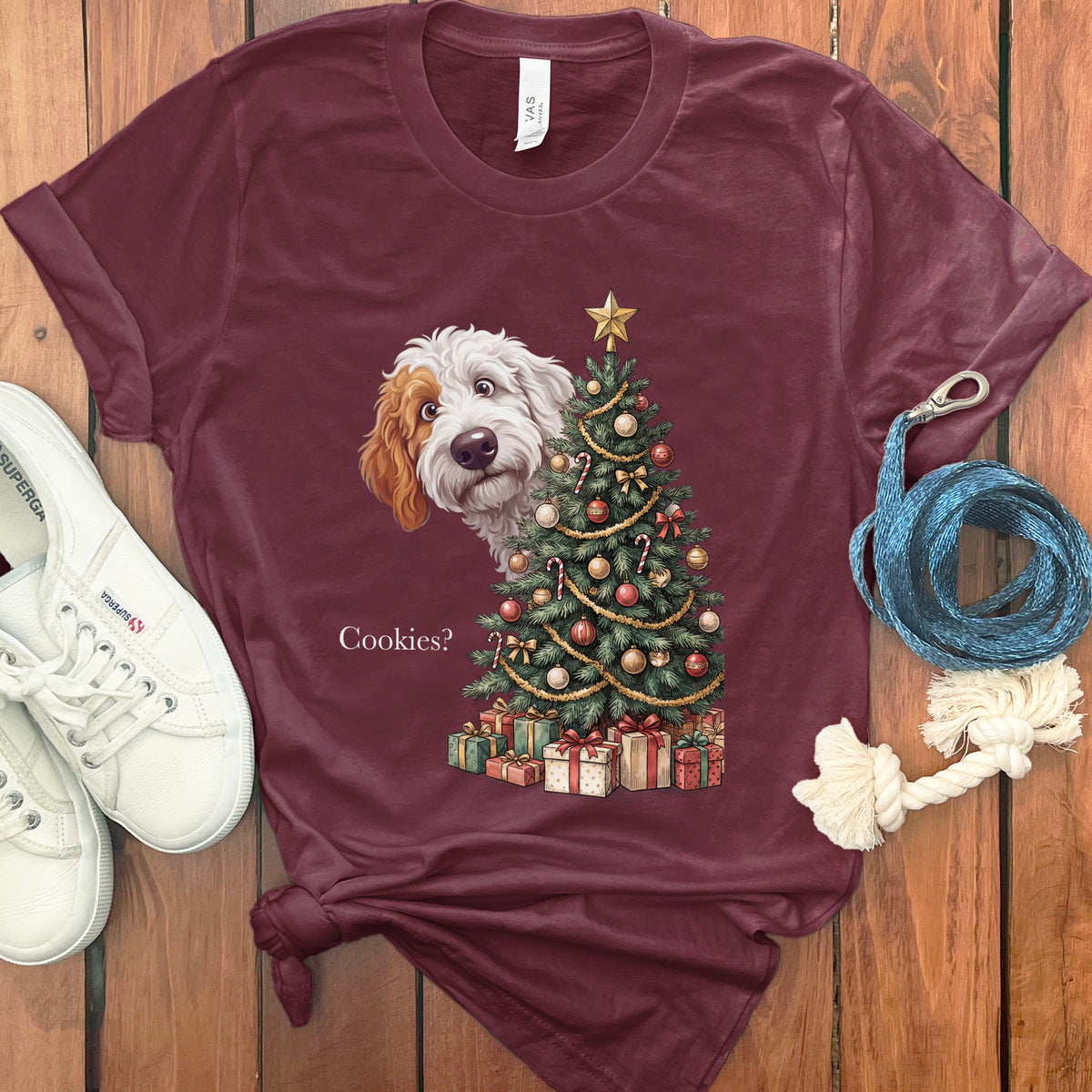 Maroon t-shirt with a doodle dog peeking behind a Christmas tree with gifts.